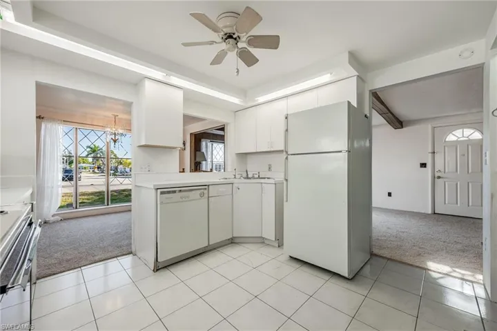 Kitchen with light colored carpet, light countertops, white appliances, and a wealth of natural light