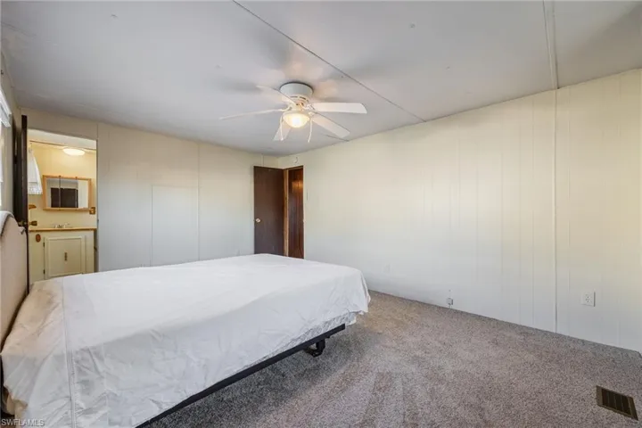 Carpeted bedroom with ensuite bath and a ceiling fan