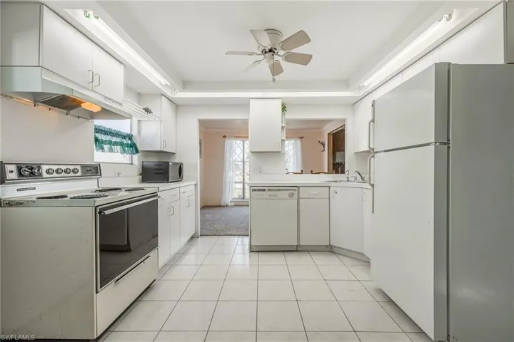 Kitchen with a sink, light countertops, ceiling fan, white appliances, and white cabinetry