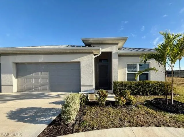 View of front of home with a garage, concrete driveway, and stucco siding