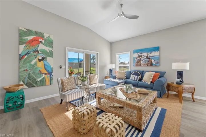 Living room with a ceiling fan, lofted ceiling, and light wood finished floors