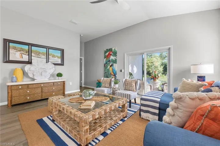 Living area with a ceiling fan, lofted ceiling, and light wood-type flooring