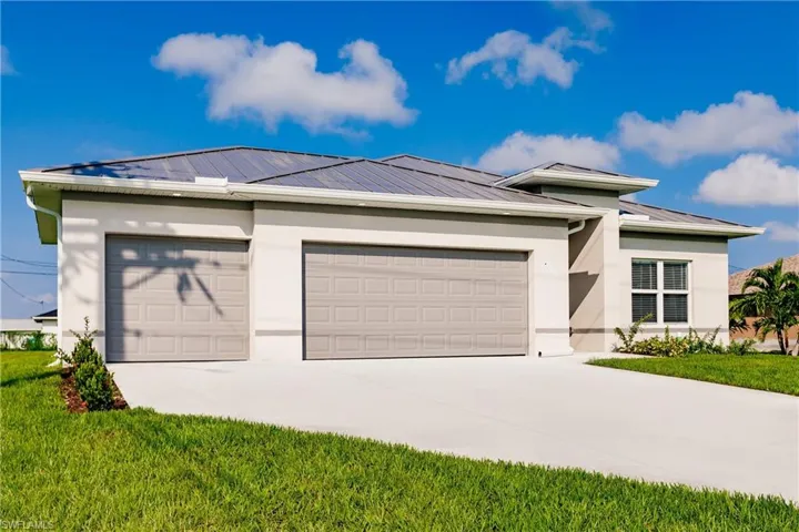 View of front facade featuring a garage, driveway, and stucco siding