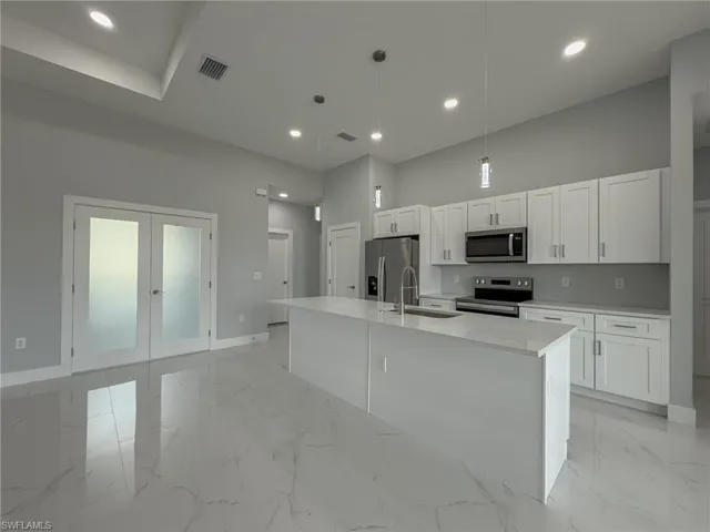 Kitchen with white cabinetry, stainless steel appliances, a sink, baseboards, and visible vents