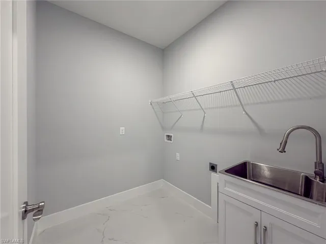 Laundry area featuring washer hookup, a sink, electric dryer hookup, baseboards, and cabinet space