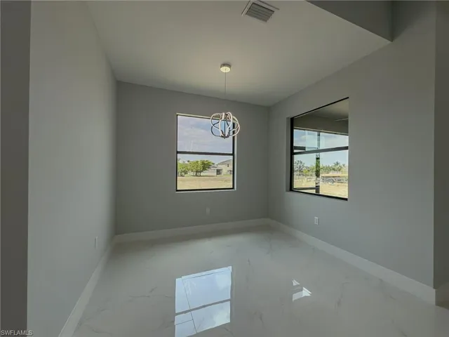 Unfurnished room featuring marble finish floor, visible vents, a chandelier, and baseboards