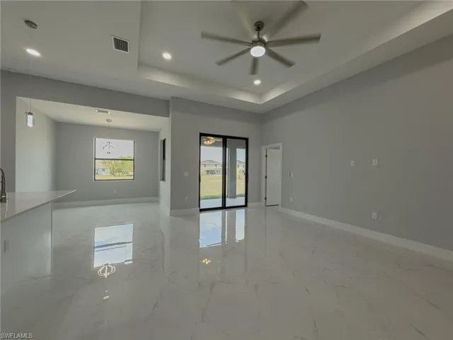 Empty room with visible vents, a ceiling fan, marble finish floor, and baseboards