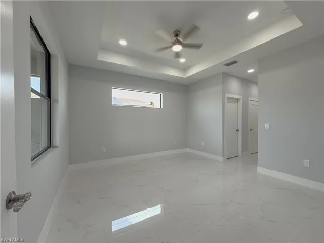 Unfurnished room with a raised ceiling, visible vents, baseboards, recessed lighting, and marble finish floor