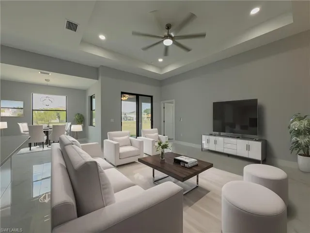 Living area featuring a ceiling fan, visible vents, a raised ceiling, baseboards, and recessed lighting