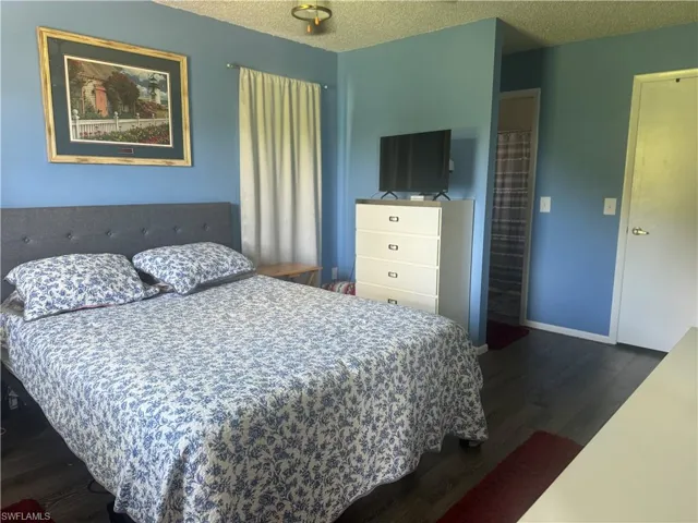Bedroom with a textured ceiling and dark hardwood / wood-style floors