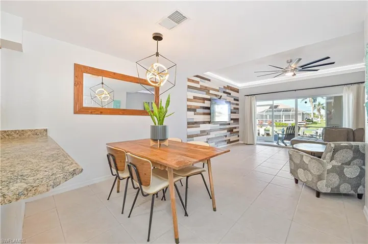Tiled dining room featuring ceiling fan with notable chandelier