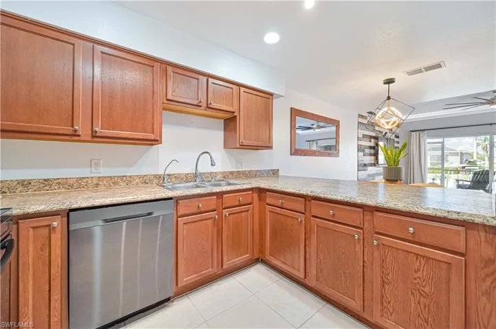 Kitchen with kitchen peninsula, stainless steel dishwasher, ceiling fan, sink, and light tile patterned floors