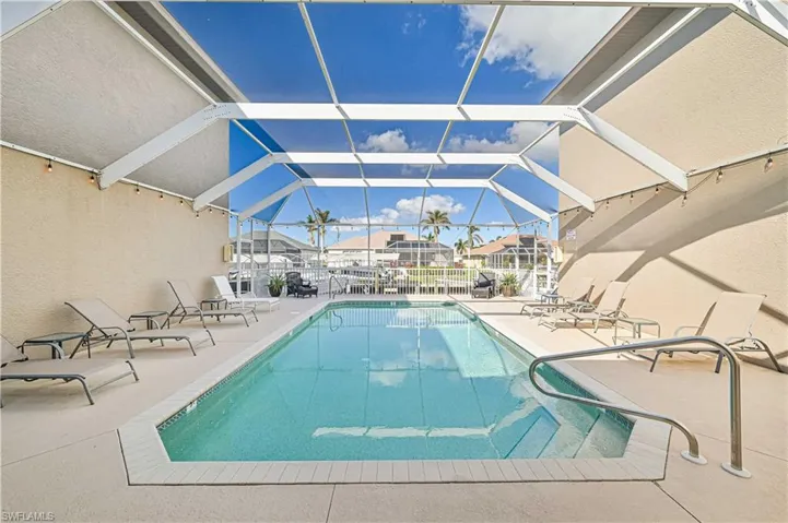 View of swimming pool with glass enclosure and a patio area