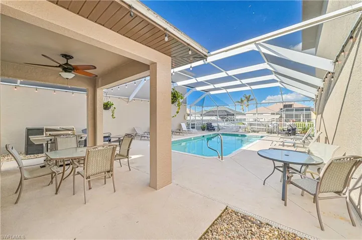 View of swimming pool featuring glass enclosure, ceiling fan, and a patio
