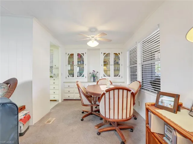 Dining area with ornamental molding, ceiling fan, and light colored carpet