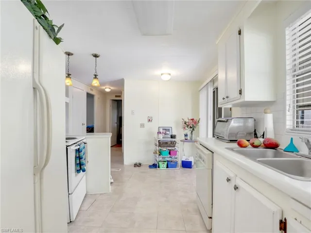 Kitchen with white cabinetry, hanging light fixtures, white appliances, backsplash, and light tile floors