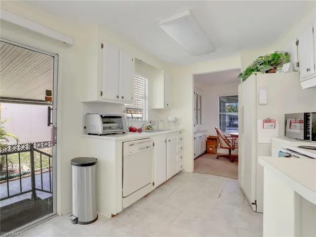 Kitchen featuring white appliances, white cabinets, sink, and light colored carpet