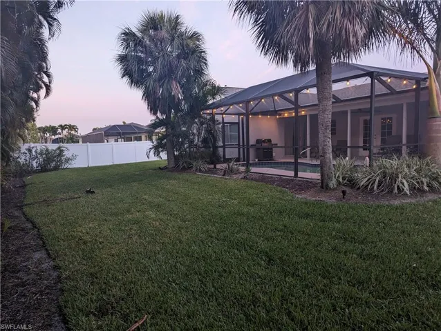 large backyard at dusk featuring a lanai