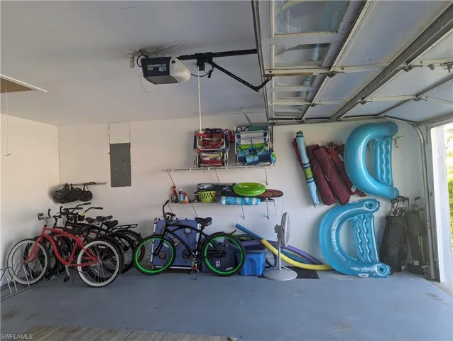 Garage featuring bikes, pool floats, beach chairs, umbrella, 2 sets of golf clubs, pickleball paddles and balls