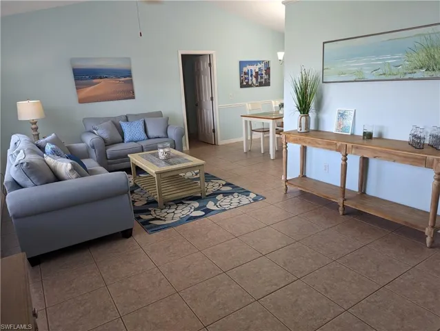 Tiled living area featuring vaulted ceiling and baseboards