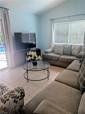 Tiled living room with vaulted ceiling, plenty of seating, TV with local channels, Amazon firestick, and DVD player