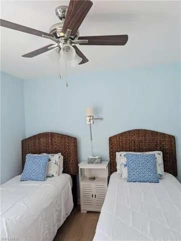 Bedroom featuring two comfortable twin beds, night table, and a ceiling fan