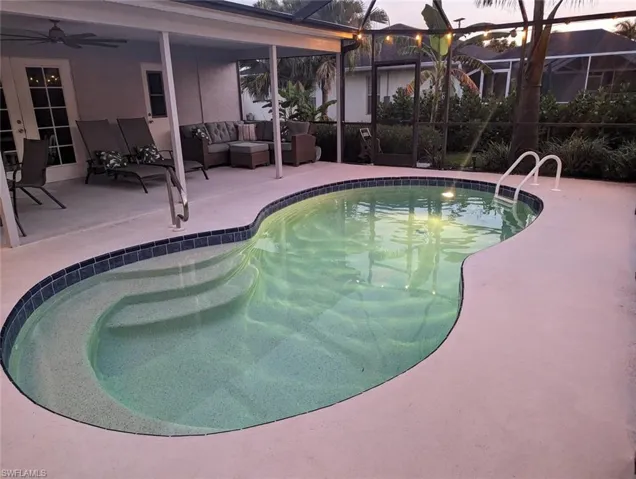 Swimming pool featuring a patio area, an outdoor hangout area, a ceiling fan, and screened enclosure