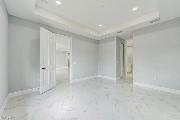 Tiled spare room featuring a tray ceiling