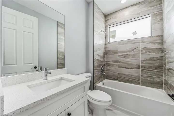 Full bathroom featuring tiled shower / bath, toilet, and large vanity