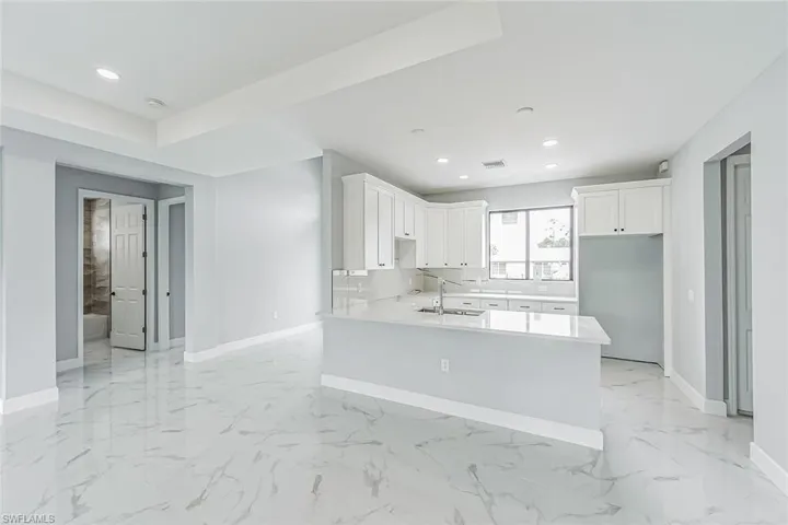 Kitchen featuring sink, white cabinetry, light tile floors, and kitchen peninsula