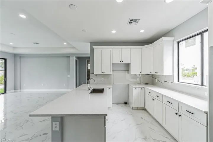 Kitchen featuring a healthy amount of sunlight, sink, backsplash, and light tile floors
