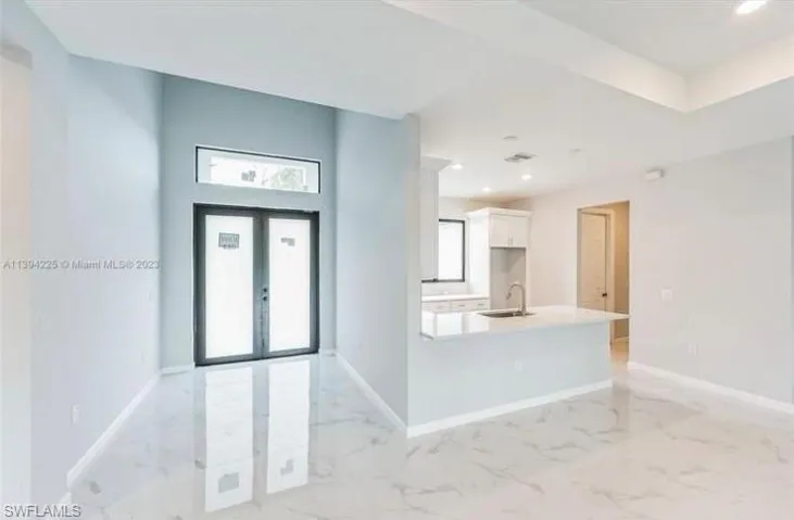Spare room featuring a raised ceiling, a wealth of natural light, and light tile floors