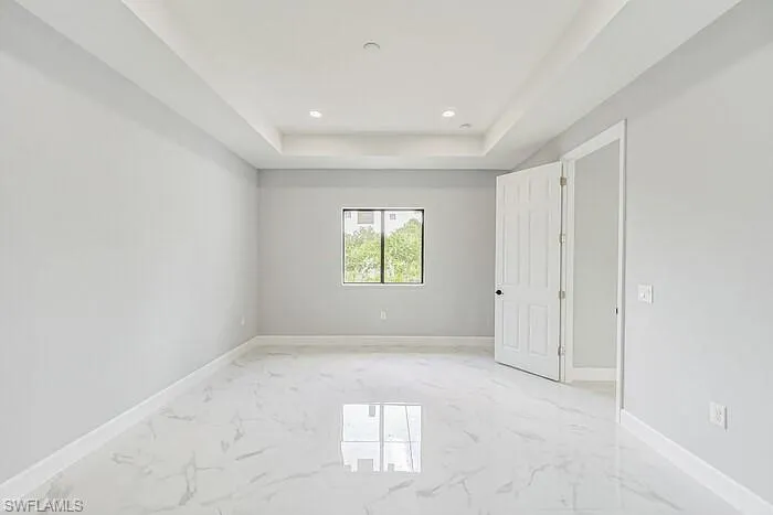 Tiled empty room featuring a tray ceiling