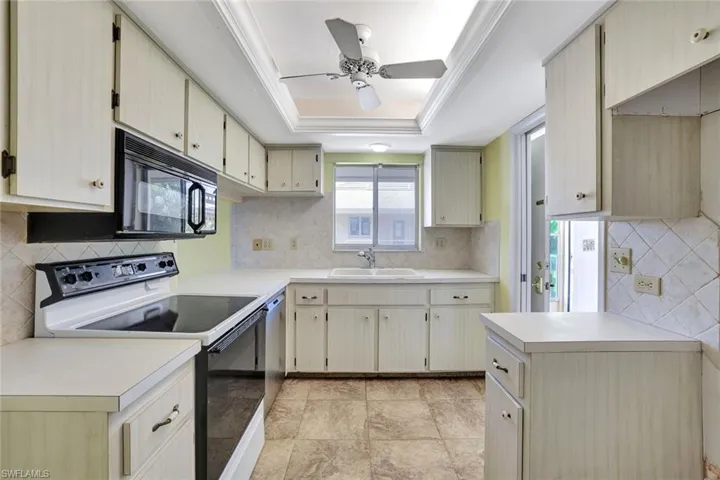 Kitchen featuring electric range oven, a sink, a ceiling fan, light countertops, and decorative backsplash