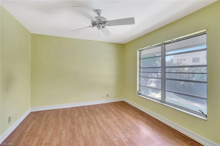 Unfurnished room with light wood-style floors, healthy amount of natural light, and a ceiling fan