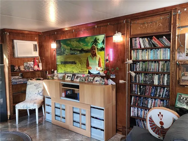 Living room with wood walls and a wall mounted air conditioner and built in Bookcases