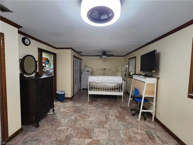 Bedroom with crown molding and stone finish floors