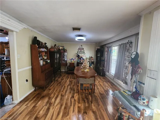 Dining room with dark wood-style flooring and ornamental molding