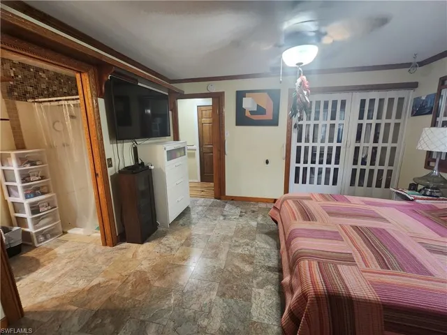 Promary Bedroom featuring crown molding, light stone finish floors, and ceiling fan