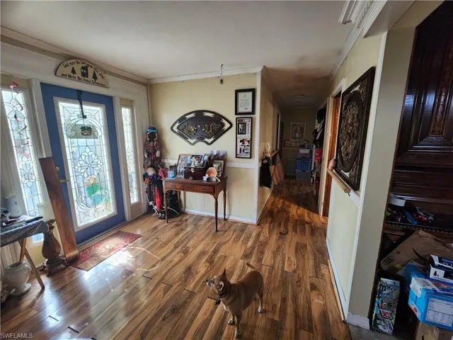 Entryway with wood finished floors, crown molding, and stairs