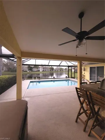 View of pool with PANORAMIC screen enclosure, a water view, ceiling fan, and a patio