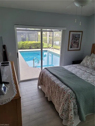 Bedroom with light wood-style tile flooring, ceiling fan, and access to outside