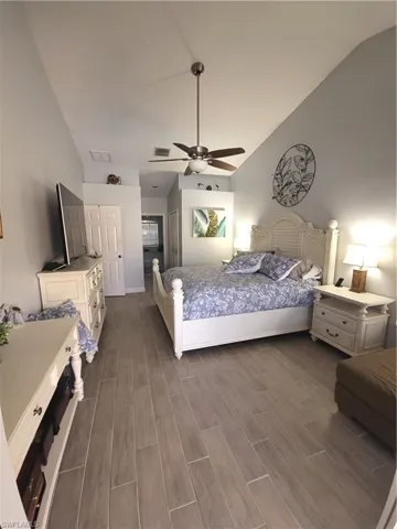 Bedroom with light wood-type tile flooring, ceiling fan, and vaulted ceiling, his/hers walk-in closets