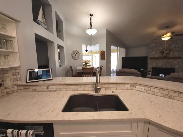 Kitchen with ceiling fan, light quartz countertops, composite sink, and vaulted ceiling.