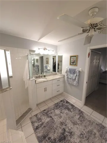 Large Bathroom with dual vanity, a tiled, walk-in shower, ceiling fan.