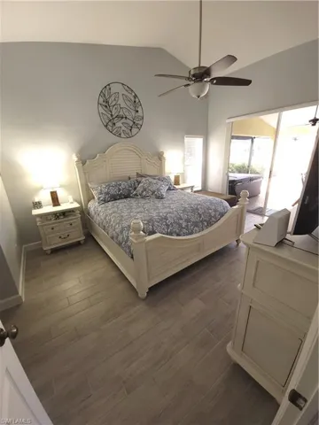 Bedroom with ceiling fan, light wood-style tile floors, and high vaulted ceiling