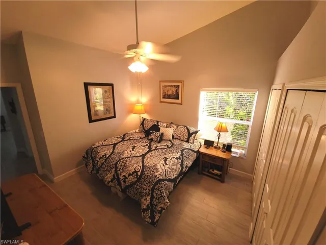 Bedroom featuring lofted ceiling, light wood-type tile flooring, large closet and ceiling fan