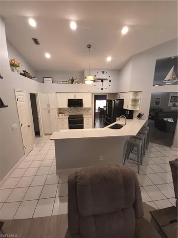 Kitchen featuring refrigerator, white cabinetry, stove, kitchen peninsula, and ceiling fan