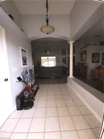 Tiled entrance foyer with ornate columns and ceiling fan and coat closet