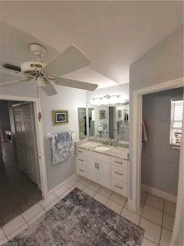 Bathroom with dual vanity, ceiling fan tile flooring and separate water closet.
